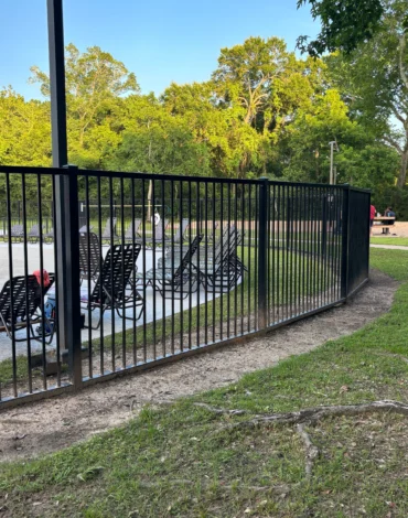 Steel fence installation showing black steel posts and panels being installed in a residential yard